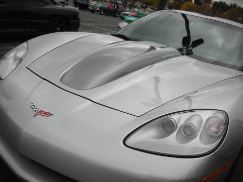1998 Ford Crown Victoria - A silver Chevrolet Corvette is parked in a lot with other vehicles visible in the background.