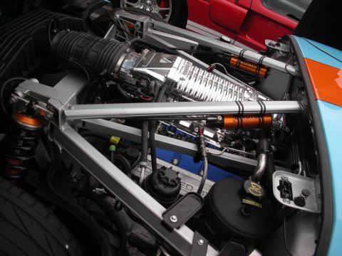 1998 Ford Crown Victoria - Close-up view of a supercharged engine bay, with a red sports car visible in the background.