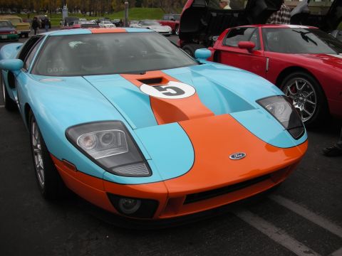 1998 Ford Crown Victoria - A light blue and orange Ford GT with racing stripes is parked next to a red Ford GT.
