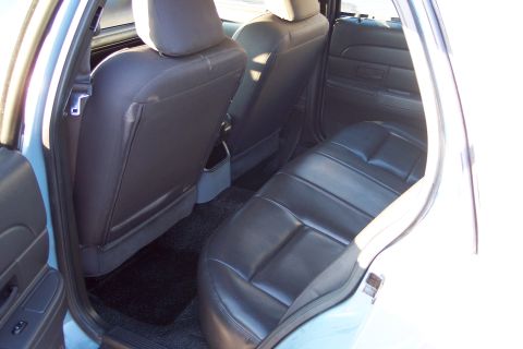2001 Ford Crown Victoria - The rear interior of a car shows black leather seats and dark carpeting.