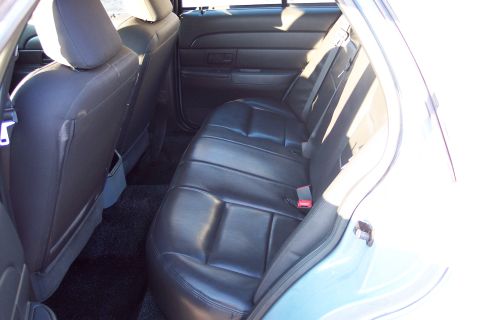 2001 Ford Crown Victoria - Rear interior view of a light blue vehicle, showing black leather seats and door panel.