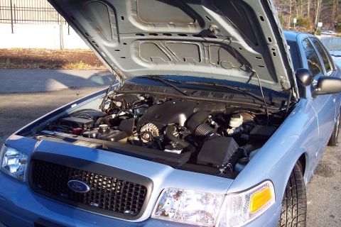2001 Ford Crown Victoria - The engine bay of a light blue 2001 Ford Crown Victoria is visible with the hood open.