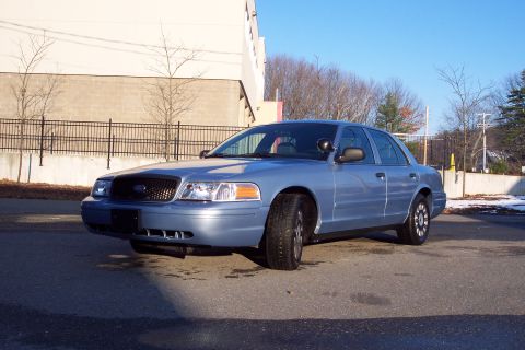 2001 Ford Crown Victoria - A silver 2001 Ford Crown Victoria is parked in front of a building on a sunny day.