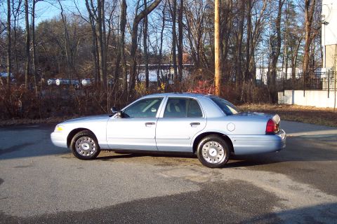 2001 Ford Crown Victoria - A white sedan is seen from the side on a sunny day with trees in the background.