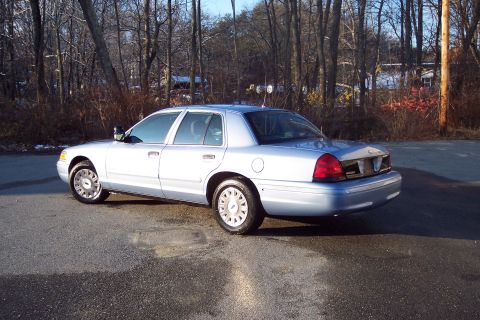 2001 Ford Crown Victoria - A white 2001 Ford Crown Victoria sedan is viewed from the rear three-quarter angle.