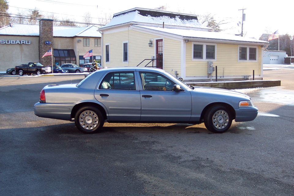 Silver 2001 Ford Crown Victoria sedan, side view, showing minor damage to the rear bumper