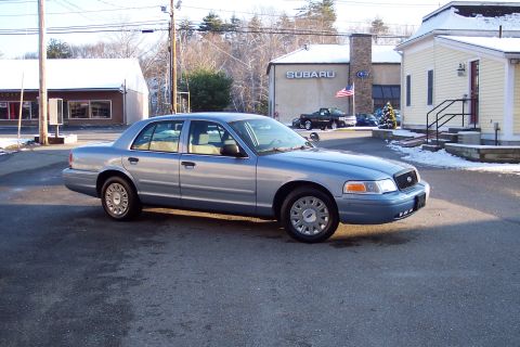 2001 Ford Crown Victoria - A silver sedan is captured in motion from a three-quarter front perspective.
