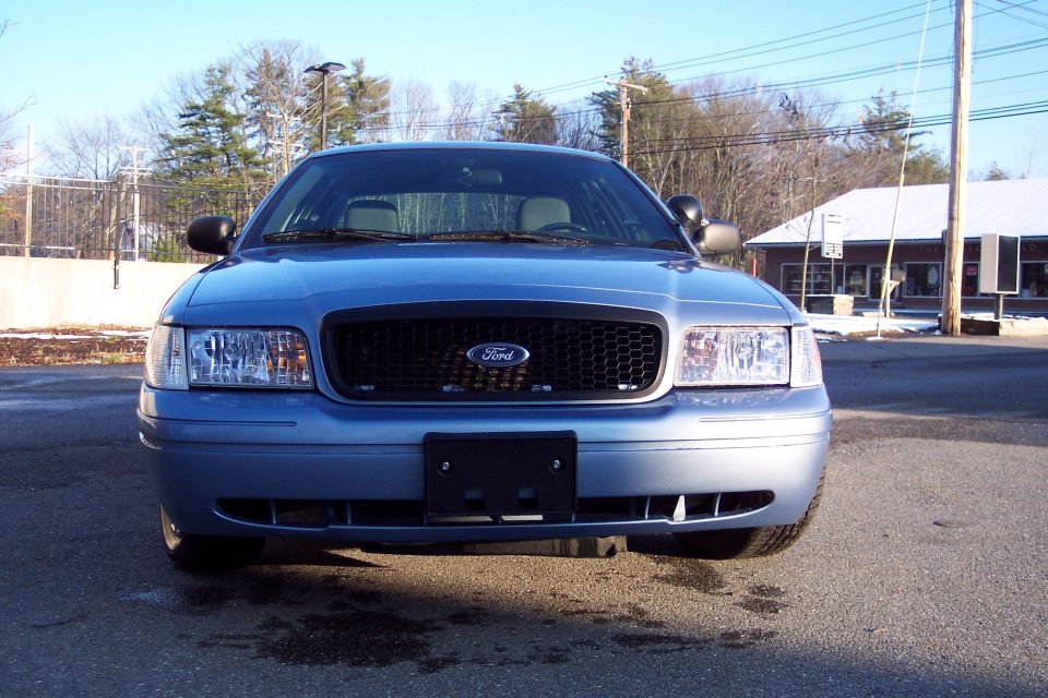Blue 2001 Ford Crown Victoria front view, grille visible, some damage to front bumper
