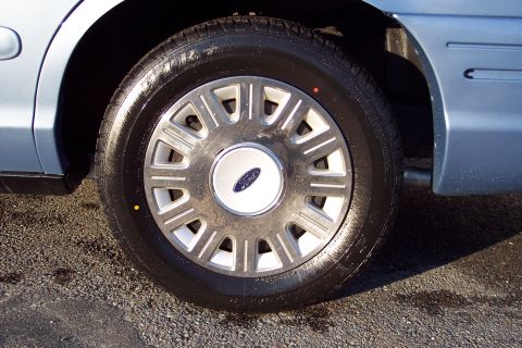 2001 Ford Crown Victoria - Close-up of the wheel and side panel of a light blue 2001 Ford Crown Victoria.