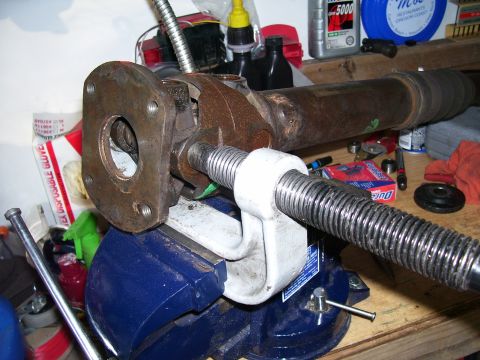 1991 Ford Bronco - A driveshaft is secured in a vise for repair work, with various tools and fluids visible in the background.