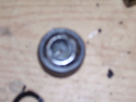 1991 Ford Bronco - A close-up of a single metal component, possibly a cap or cover, resting on a wooden surface.