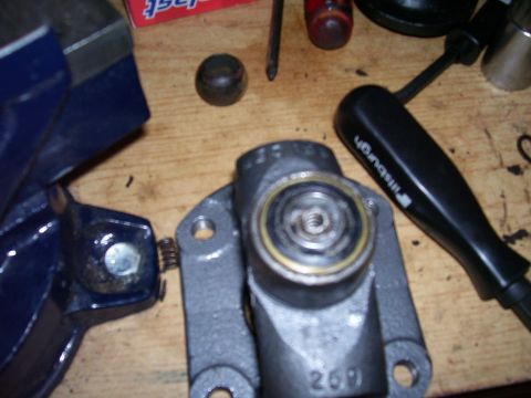 1991 Ford Bronco - Close-up of a brake caliper part being worked on, secured in a vise with tools present.