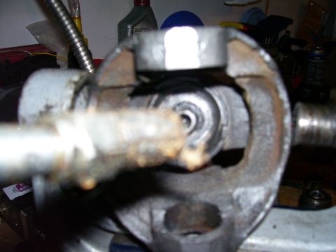 1991 Ford Bronco - Extreme close-up of a driveshaft U-joint being pressed apart in a bench vise, with a socket used as a driver against the cap and the expose…