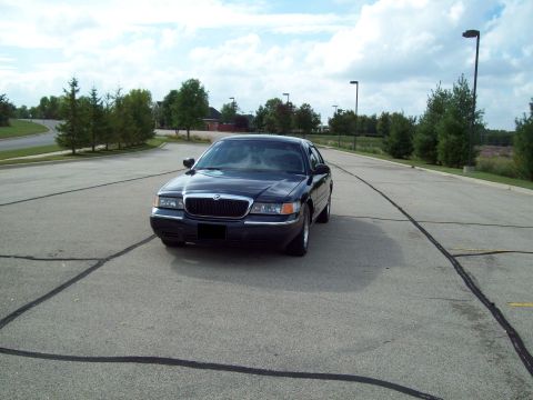 1999 Mercury Grand Marquis - 1999 Mercury Grand Marquis parked in an empty lot under a cloudy sky.