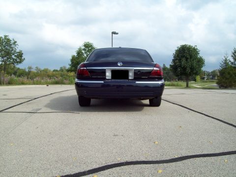 1999 Mercury Grand Marquis - Rear view of a dark blue Mercury Grand Marquis sedan parked on an open asphalt lot, showing its chrome trim, Mercury emblem, and blacked-ou…