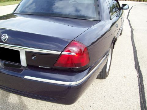 1999 Mercury Grand Marquis - The rear of a dark blue sedan with tinted tail lights is visible from a rear quarter angle.