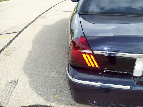 1999 Mercury Grand Marquis - Close-up of the rear taillight of a dark blue Mercury Grand Marquis LS showing illuminated amber turn-signal segments and badge.