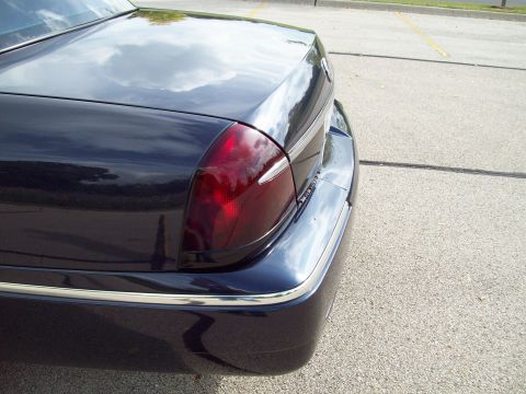 1999 Mercury Grand Marquis - Close-up of the polished dark blue rear quarter panel and red taillight of a Mercury Grand Marquis sedan in a parking lot.