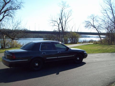 1999 Mercury Grand Marquis - Sedan parked by the water with a bridge overhead.