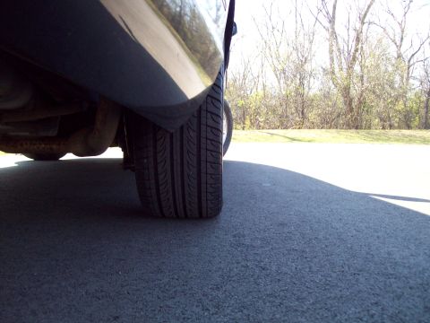 1999 Mercury Grand Marquis - Low angle view of a vehicle's rear tire and exhaust system against an asphalt background.