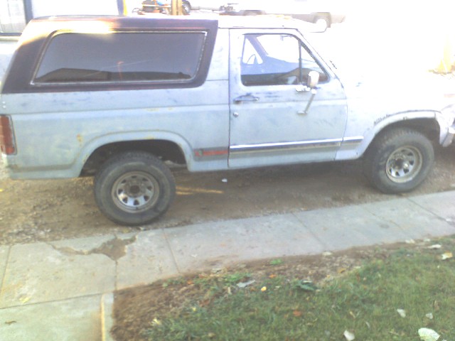 Light blue Ford Bronco with a black top, seen from the side