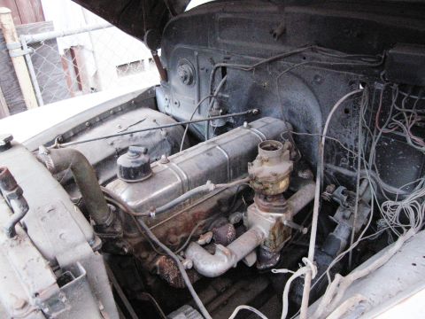 1986 Ford Bronco - The engine bay of an older vehicle shows an inline six-cylinder engine with visible wiring and hoses.