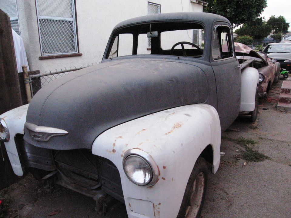 Gray and white pickup truck with a chrome grille, missing its front bumper and grille insert