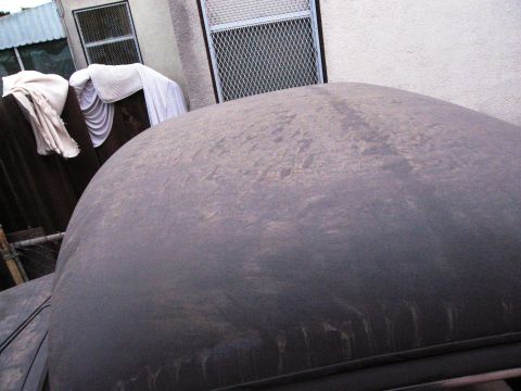 1986 Ford Bronco - The vehicle's roof is covered in a thick layer of dust, obscuring its details.