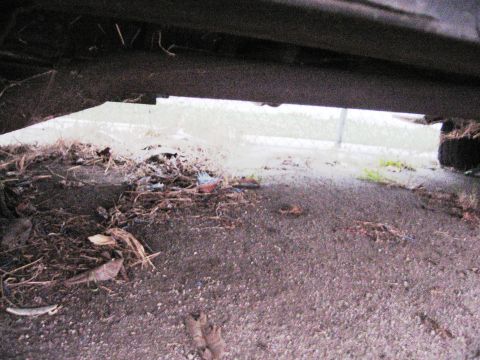 1986 Ford Bronco - The underside of a vehicle is visible, with debris scattered on the ground below.