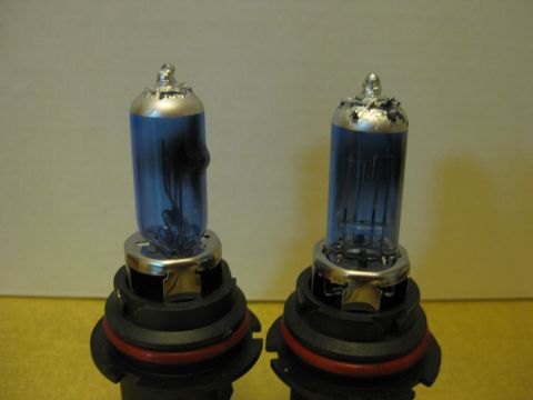 1994 Ford Thunderbird - Two automotive headlight bulbs are shown against a neutral background.