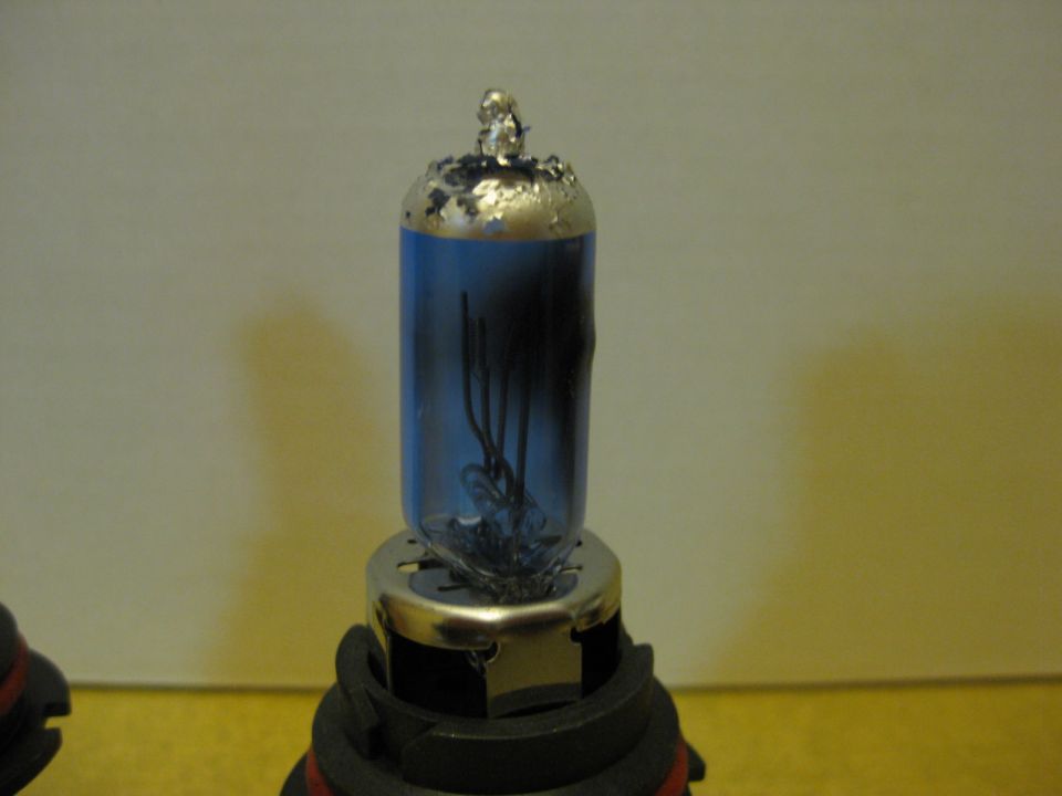 Close-up of a blue-tinted automotive headlight bulb with visible filament wires