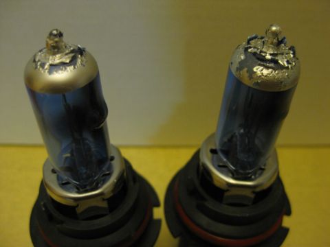 1994 Ford Thunderbird - Close-up of two automotive headlight bulbs, showing wear and damage on the metal caps.