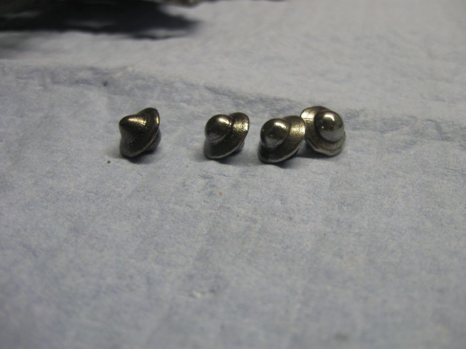 Five small mushroom-shaped carburetor metal parts laid on a blue shop towel
