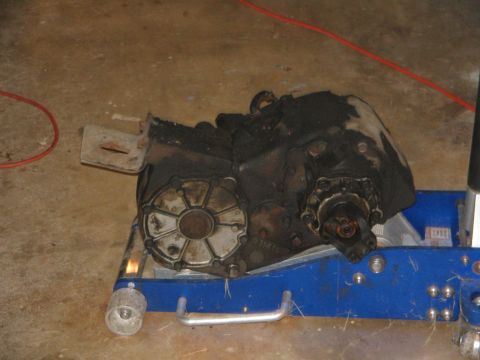 1978 Ford Bronco - A greasy transfer case is shown resting on a blue hydraulic jack.