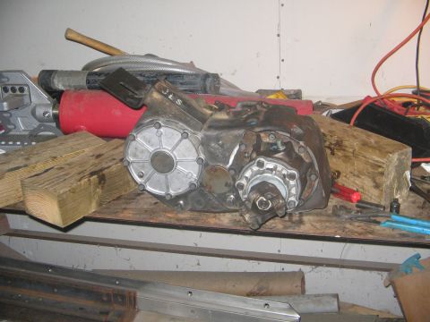 1978 Ford Bronco - Transfer case with JLS marking sits on a workbench next to various tools and wood blocks.