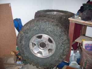 1991 Jeep Wrangler - Two off-road tires with chrome rims are visible, with a "SUPERMOTORS" watermark on the lower tire.