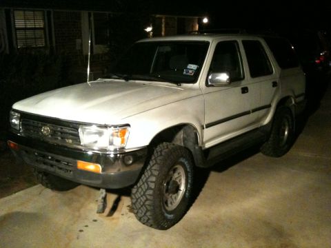 1993 Toyota 4Runner - A white 1993 Toyota 4Runner SUV is parked outside a brick house at night, showing its front and side profile.