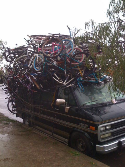 1968 Ford Mustang - A black van is completely covered by a precarious stack of bicycles, suggesting an unusual transport method.