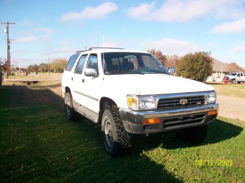 1993 Toyota 4Runner - A white 1993 Toyota 4Runner is parked on a grassy area under a blue sky with scattered clouds.