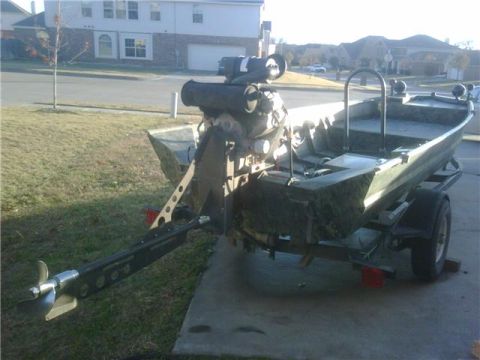 2006 Ford F-250 - A boat with an outboard motor is parked on a trailer on a concrete surface.