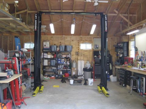 1996 Ford Bronco - A workshop scene a two-post car lift, tool chests, and storage shelves.