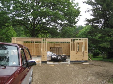 1996 Ford Bronco - A red SUV is parked in front of a partially built garage with a trailer inside.