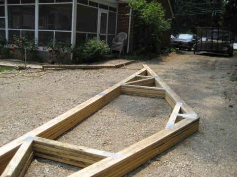 1996 Ford Bronco - A wooden truss frame lies on a gravel driveway, with two vehicles visible in the background.