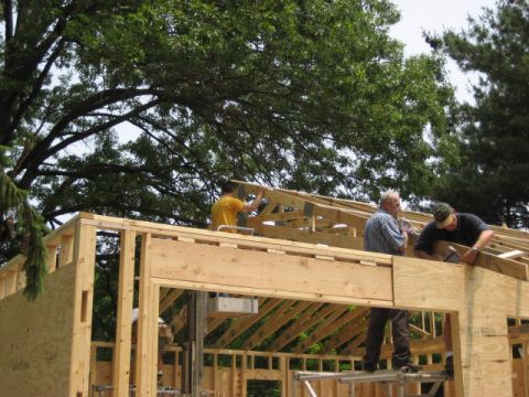 1996 Ford Bronco - Workers are actively constructing a wooden building, with framing and roof trusses visible.