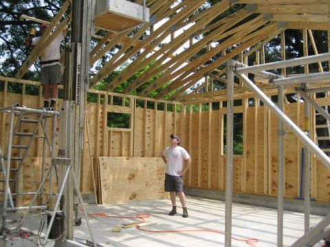 1996 Ford Bronco - Workers are busy with construction inside a building with exposed wood framing and roof trusses.