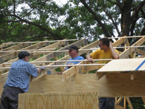 1996 Ford Bronco - Men are working on the wooden framing of a roof under a canopy of trees.