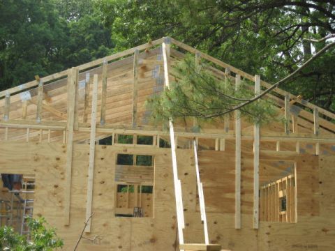 1996 Ford Bronco - Framing for a new house is visible, with plywood walls and roof structure against a backdrop of trees.