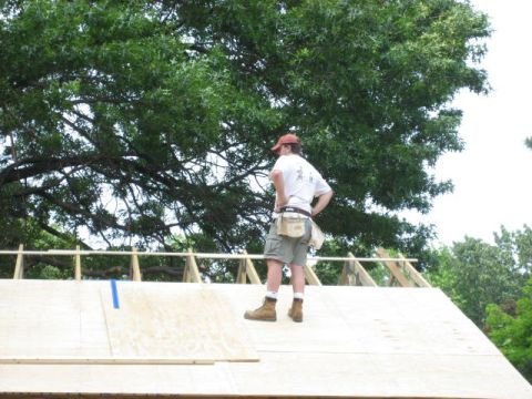 1996 Ford Bronco - A worker supervises roof construction beneath a canopy of green leaves.