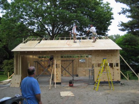 1996 Ford Bronco - Workers are actively constructing a garage, with some on the roof and others working on the framing, framing, and a yellow ladder visible.