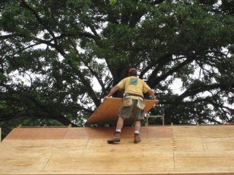 1996 Ford Bronco - A worker places plywood on a roof under a large tree.